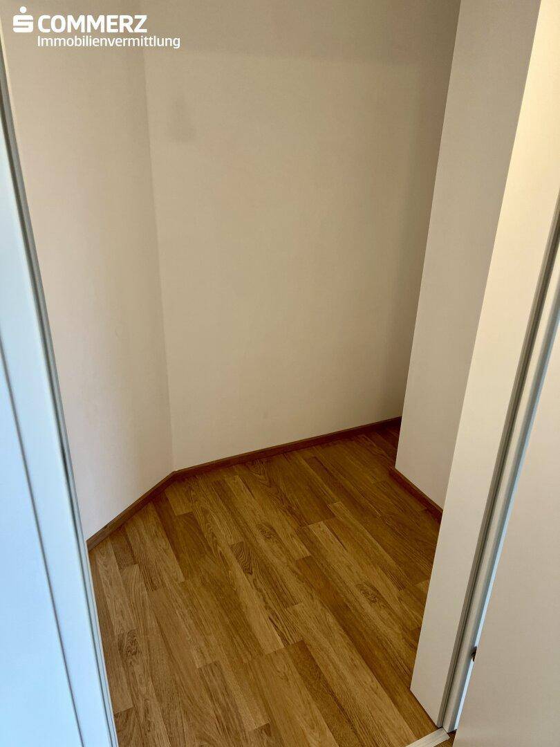 Kleiner Abstellraum mit Laminatboden und weißen Wänden.