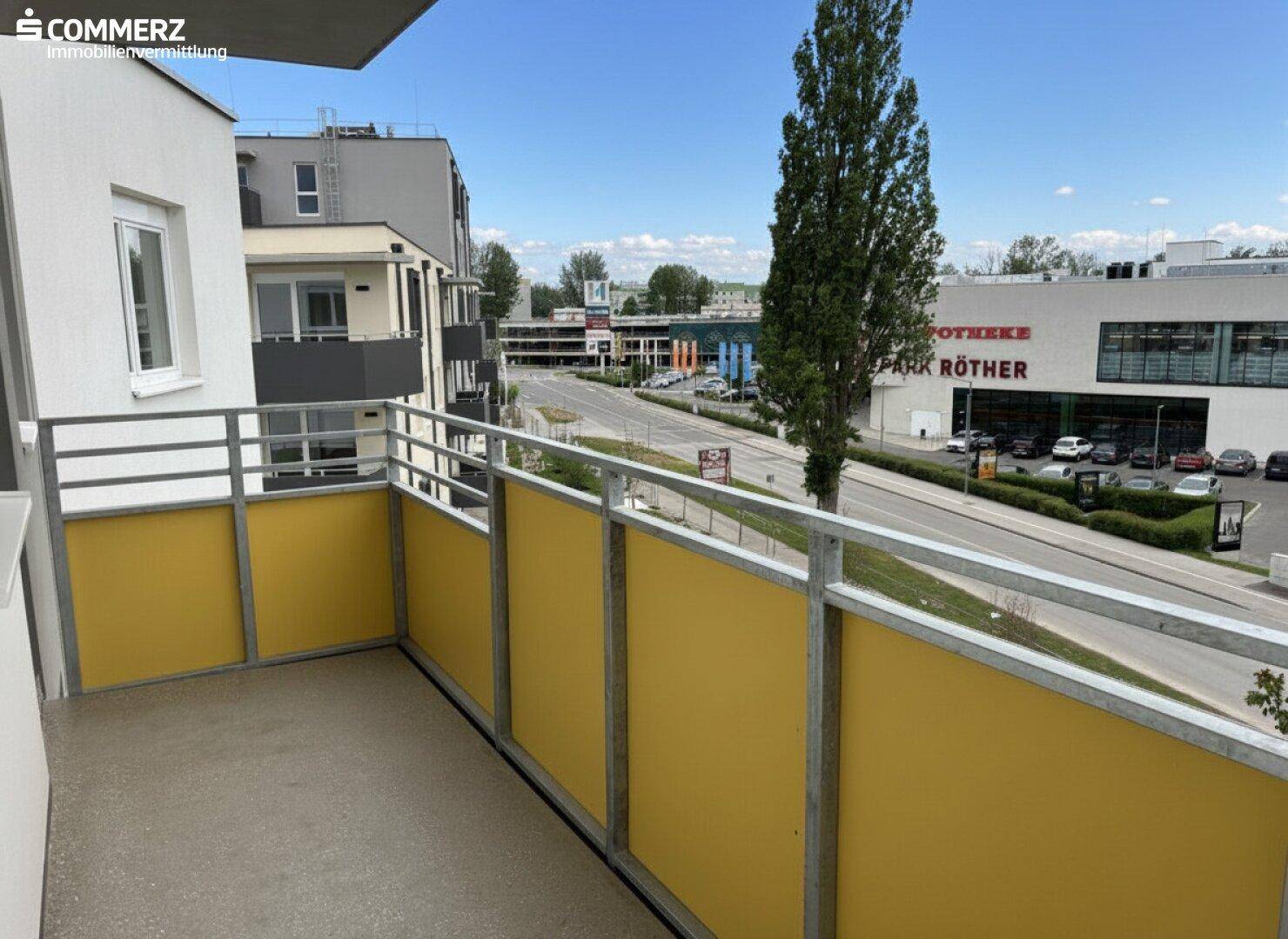 Balkon mit gelben Brüstungselementen und Blick auf die Straße.