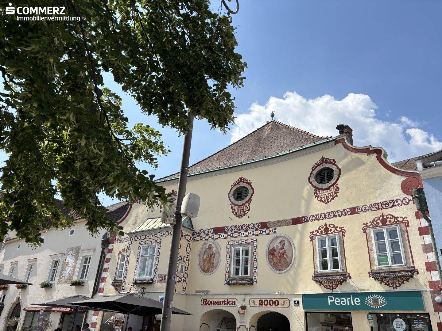 Detailansicht einer historischen Gebäudefassade mit kunstvollen Verzierungen und traditionellen Fenstern.
