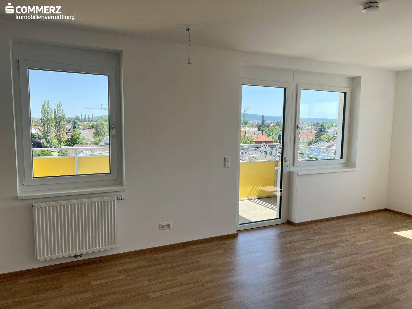 Heller Wohnbereich mit Zugang zum Balkon und weitem Blick über die Umgebung.