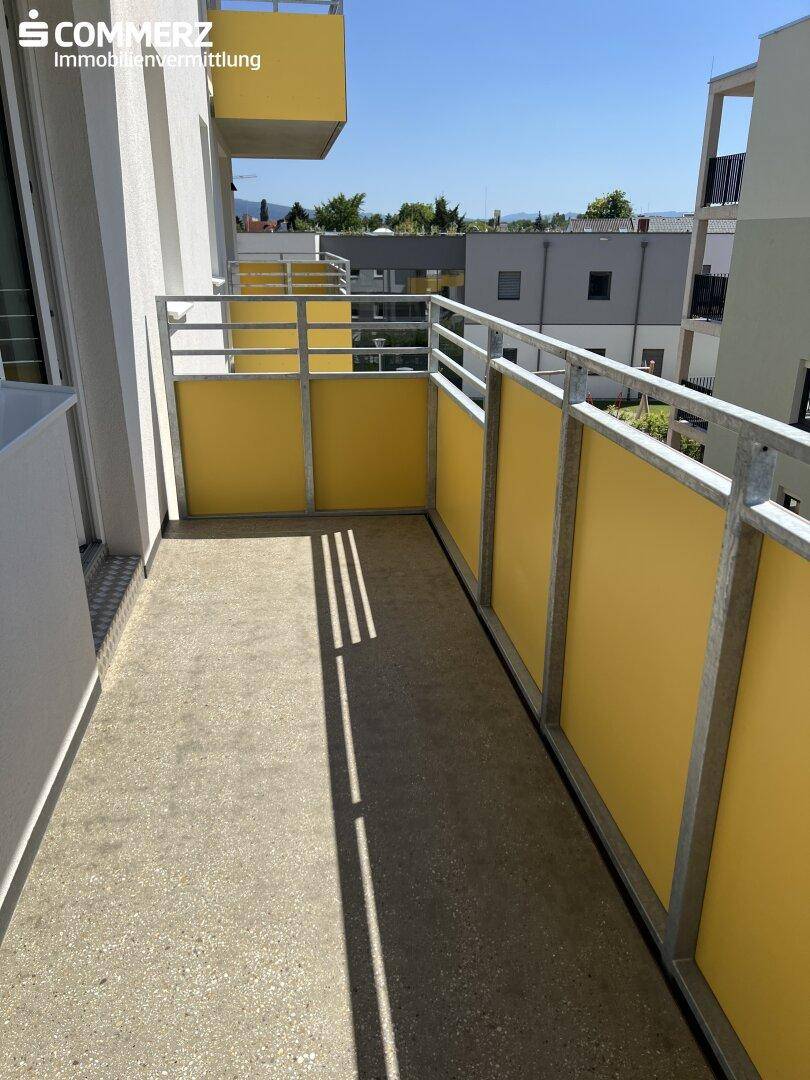 Sonniger Balkon mit gelben Paneelen und Metallgeländer, bietet einen angenehmen Außenbereich.