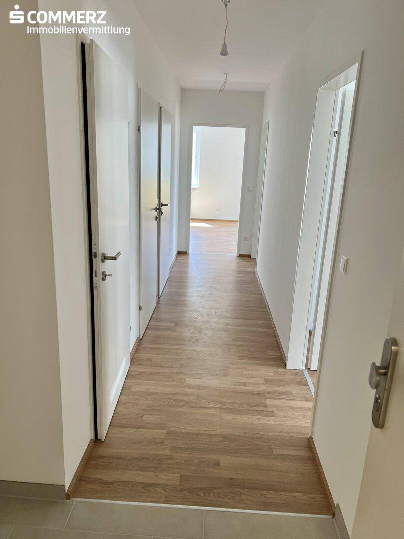 Heller Flur mit Laminatboden und mehreren Türen, der zu weiteren Räumen führt.