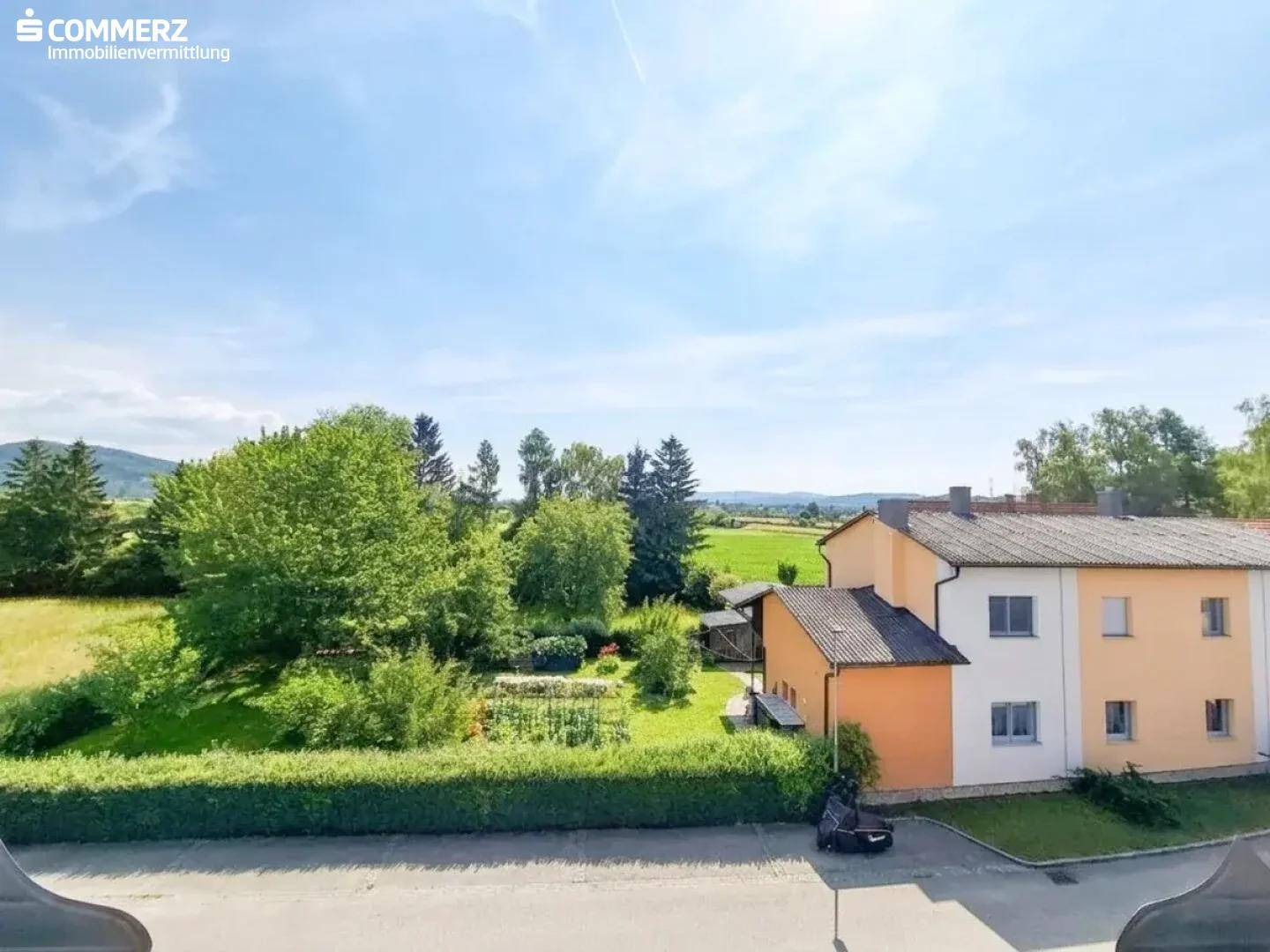 Weitläufiger Blick über grüne Felder und ländliche Umgebung unter strahlend blauem Himmel.