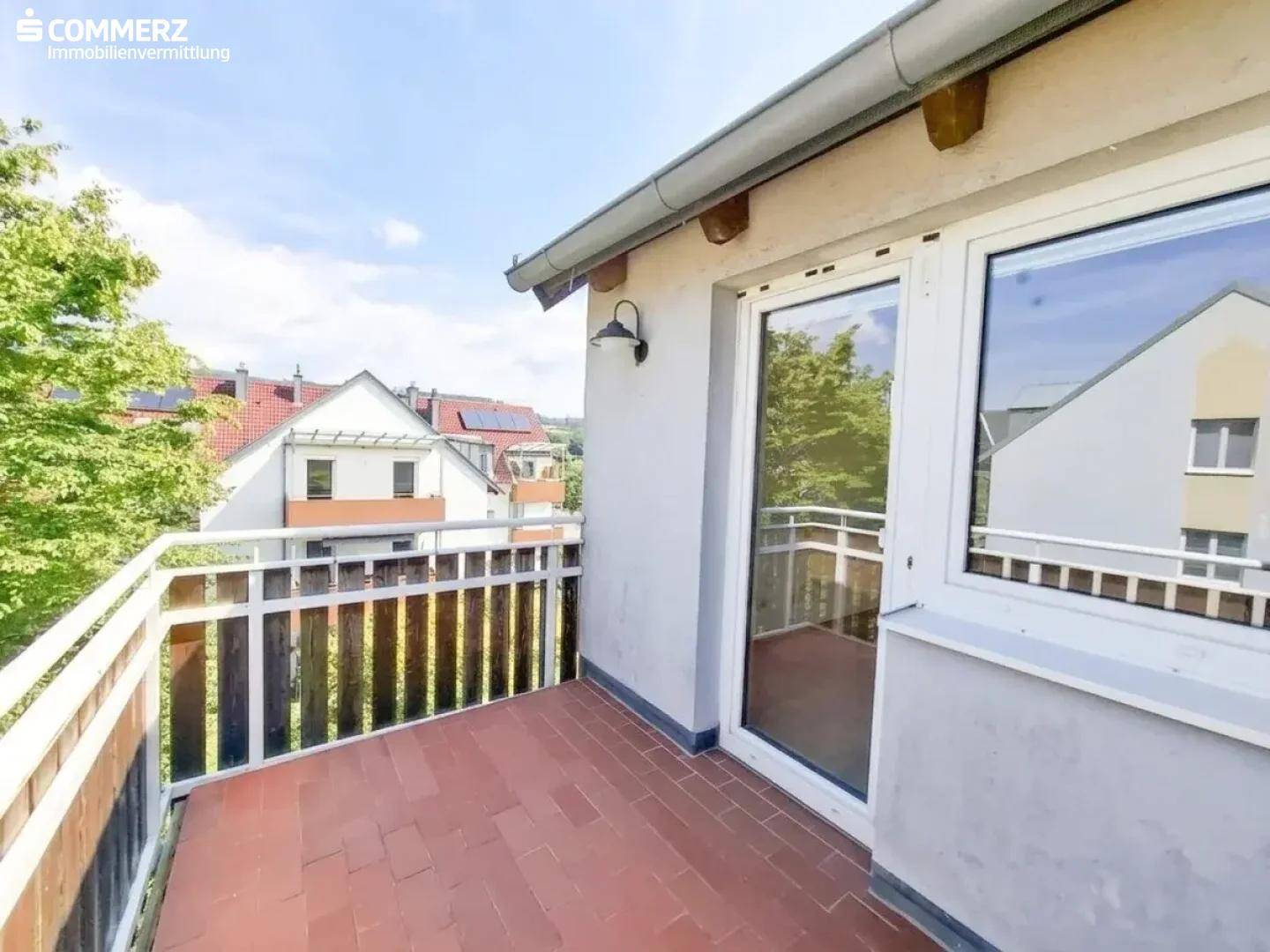Kleiner Balkon mit Fliesenboden und Holzelementen, bietet einen Blick auf die Umgebung.