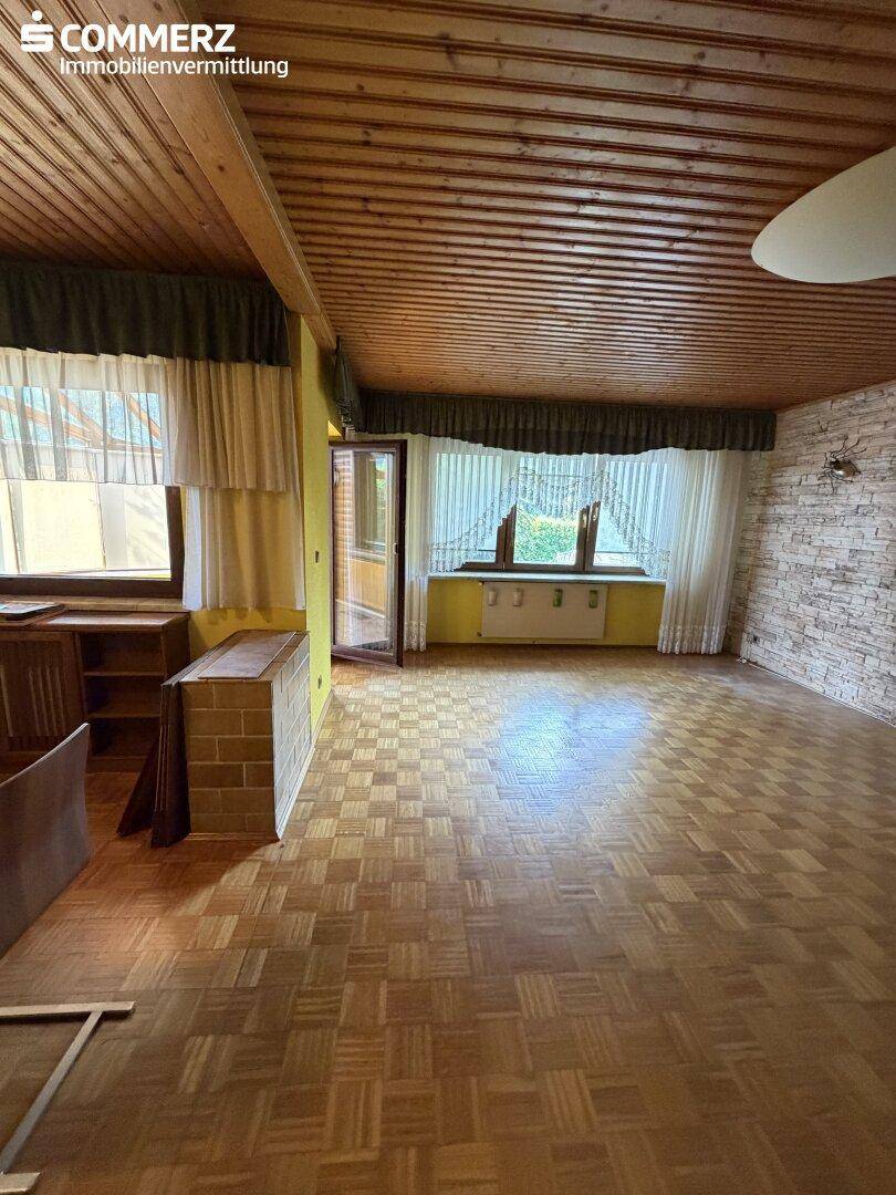 Helles Wohnzimmer mit Parkettboden, Holzdecke und Zugang zu einem Wintergarten.