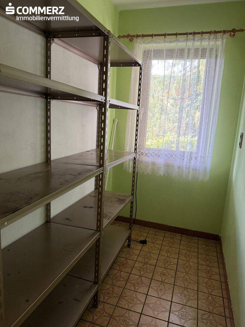 Praktischer Abstellraum mit Metallregalen, Fliesenboden und Fenster für Tageslicht.