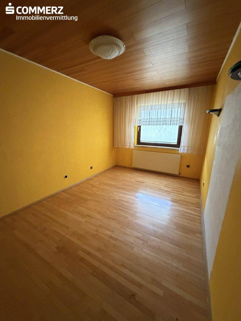 Schlafzimmer mit gelben Wänden, Holzdecke und hellem Parkettboden.