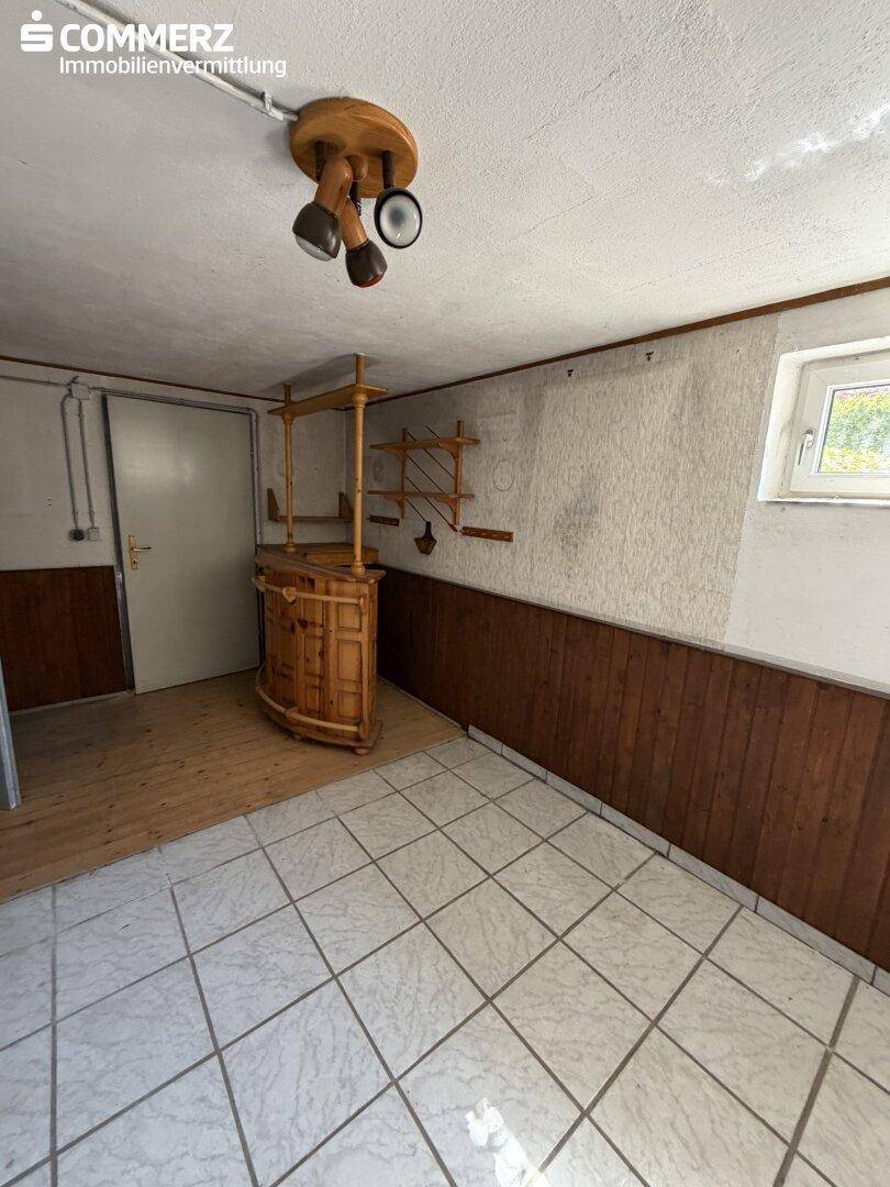 Kellerraum mit kleiner Holzbar, Fliesenboden und Fenster.