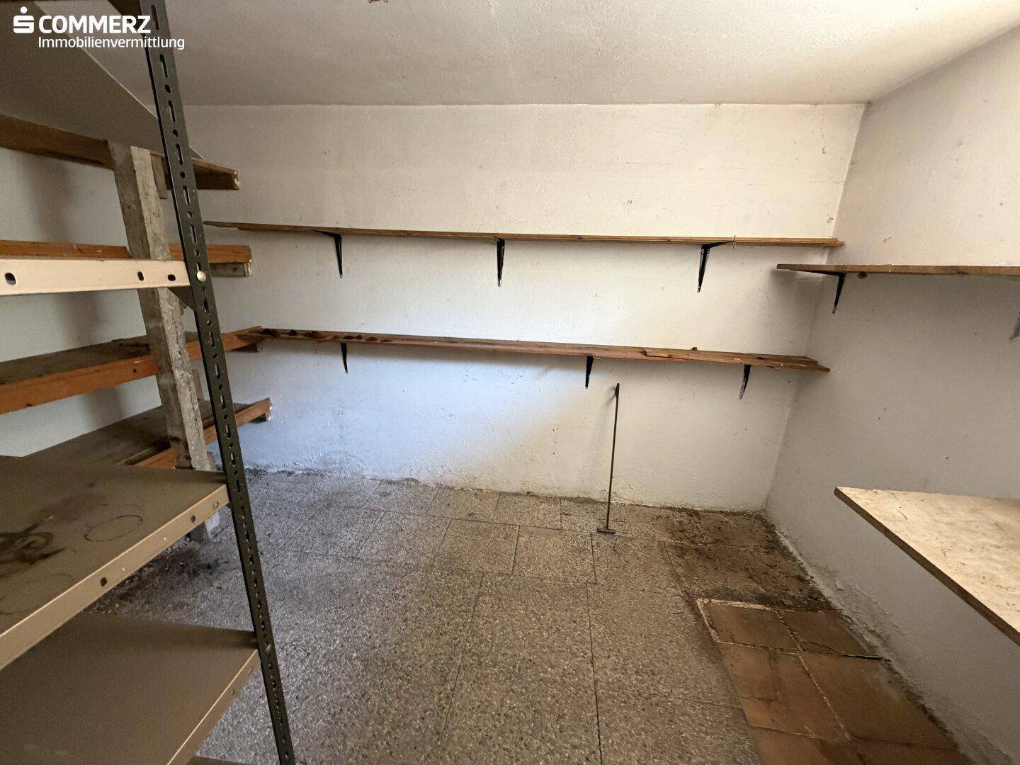 Abstellraum im Keller mit Regalen und einfachem Estrichboden.
