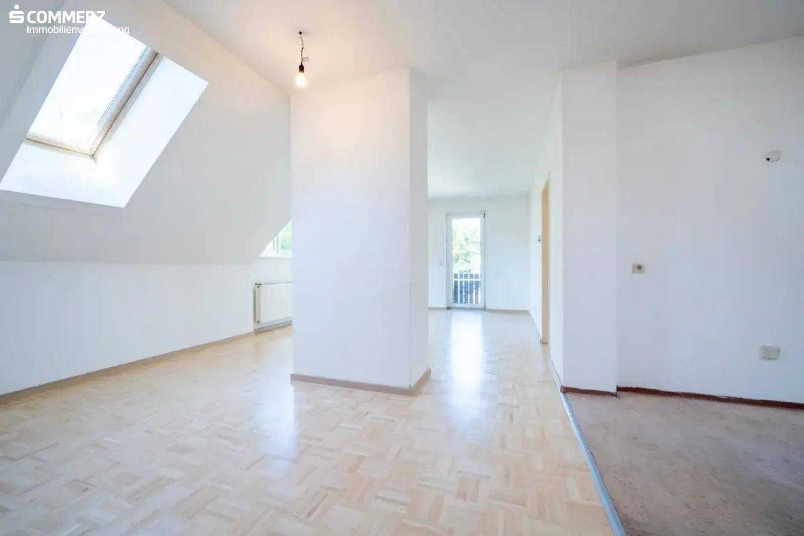 Geräumiges Dachgeschosszimmer mit Parkettboden, Dachfenster und viel natürlichem Licht.