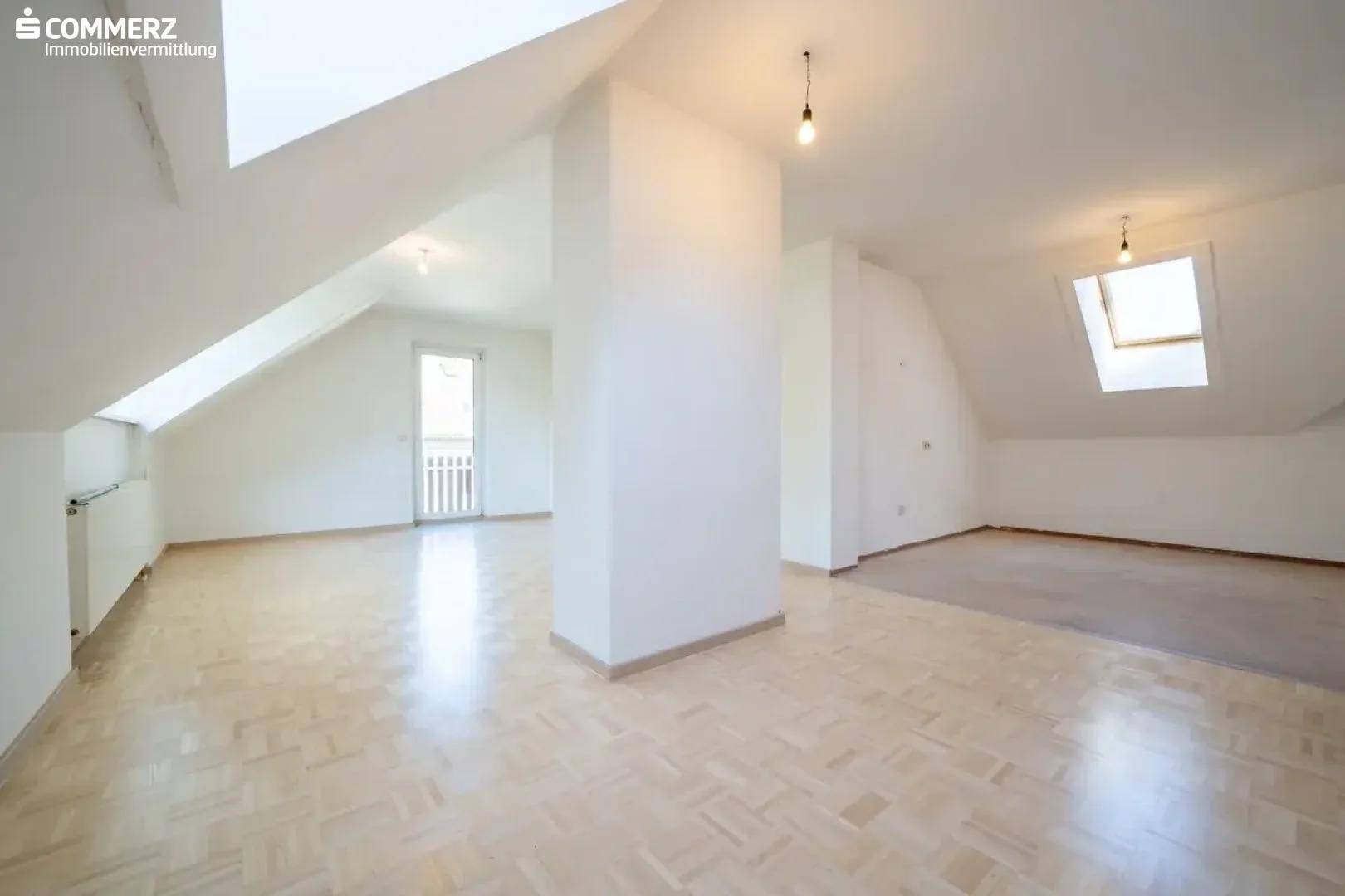 Weitläufiges Dachgeschosszimmer mit Parkettboden, Dachschrägen und viel Tageslicht.