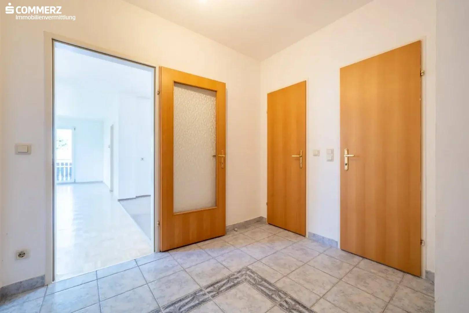 Heller Flur mit Fliesenboden und Holztüren, der zu verschiedenen Räumen führt.