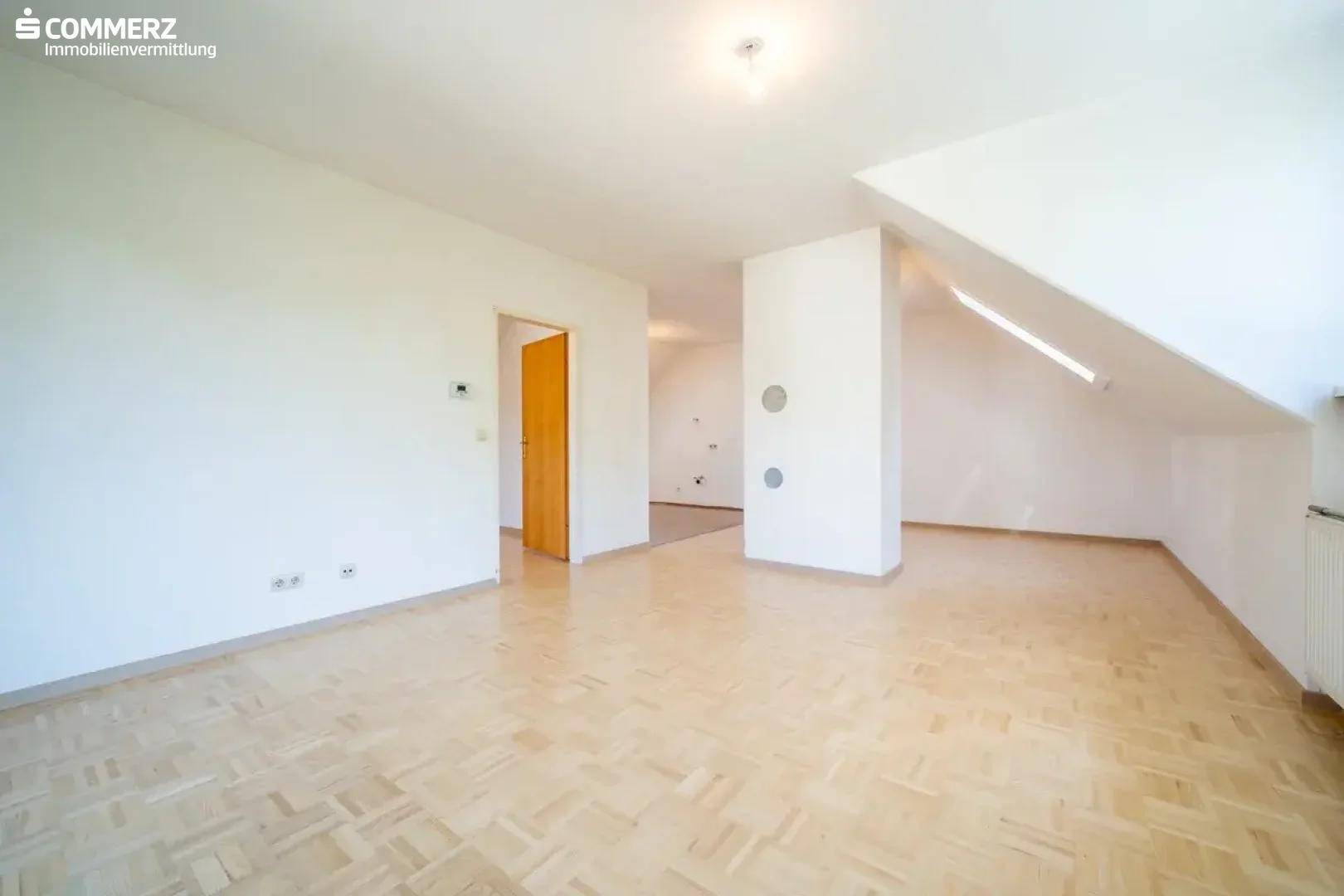Heller Dachgeschossraum mit Parkettboden und weiß gestrichenen Wänden, bereit zur individuellen Gestaltung.