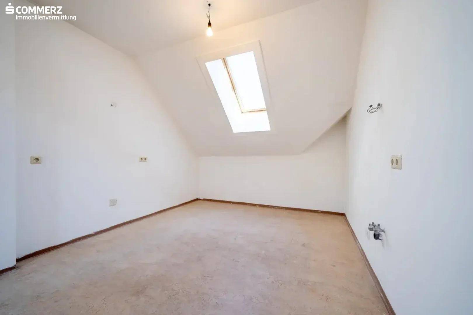 Dachgeschosszimmer mit Teppichboden, Dachfenster und Anschlüssen an der Wand.