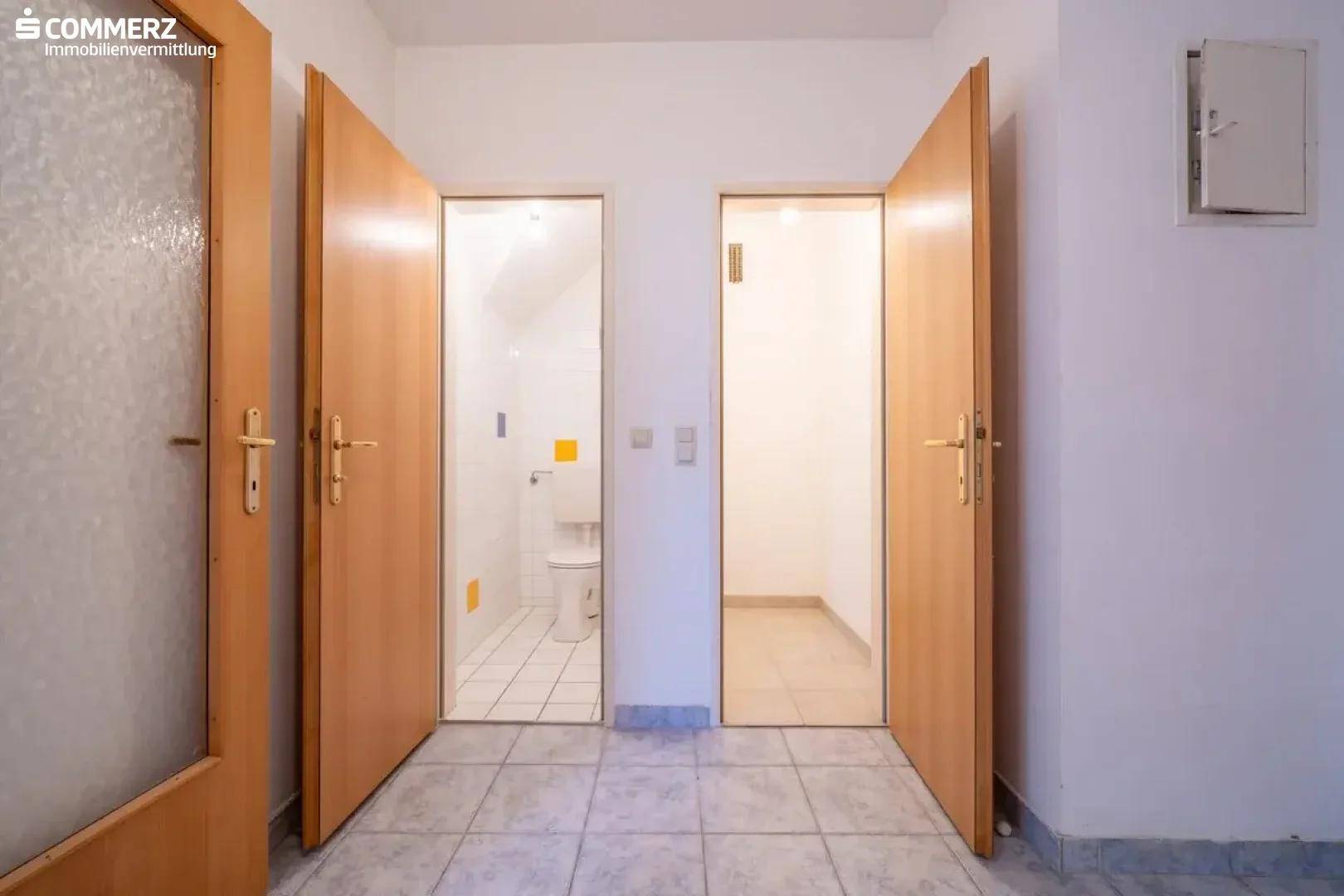 Flur mit Fliesenboden und offenen Türen, die den Zugang zu Bad und WC ermöglichen.