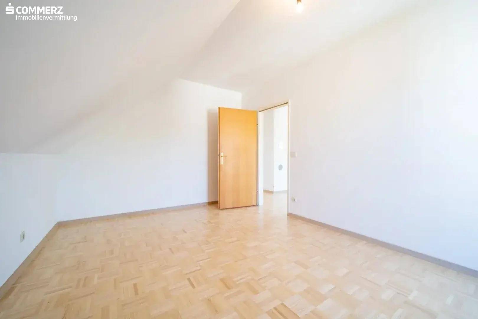 Helles Dachgeschosszimmer mit Parkettboden und weiß gestrichenen Wänden, bereit zur Nutzung.