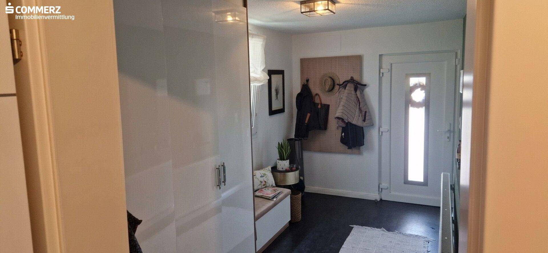 Heller Eingangsbereich mit Garderobe, Sitzbank und dunklem Bodenbelag.