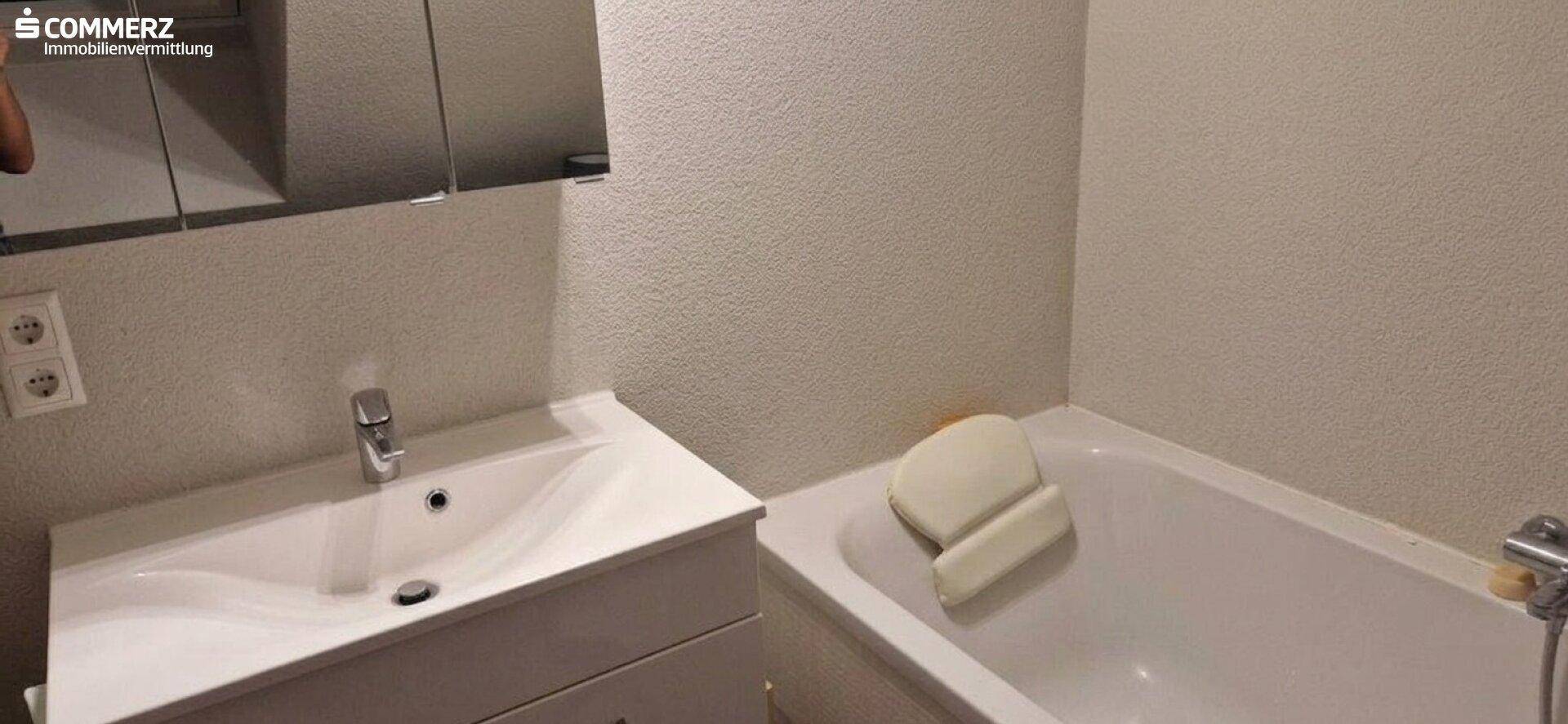 Funktionales Badezimmer mit Badewanne, Einzelwaschbecken und Spiegelschrank.