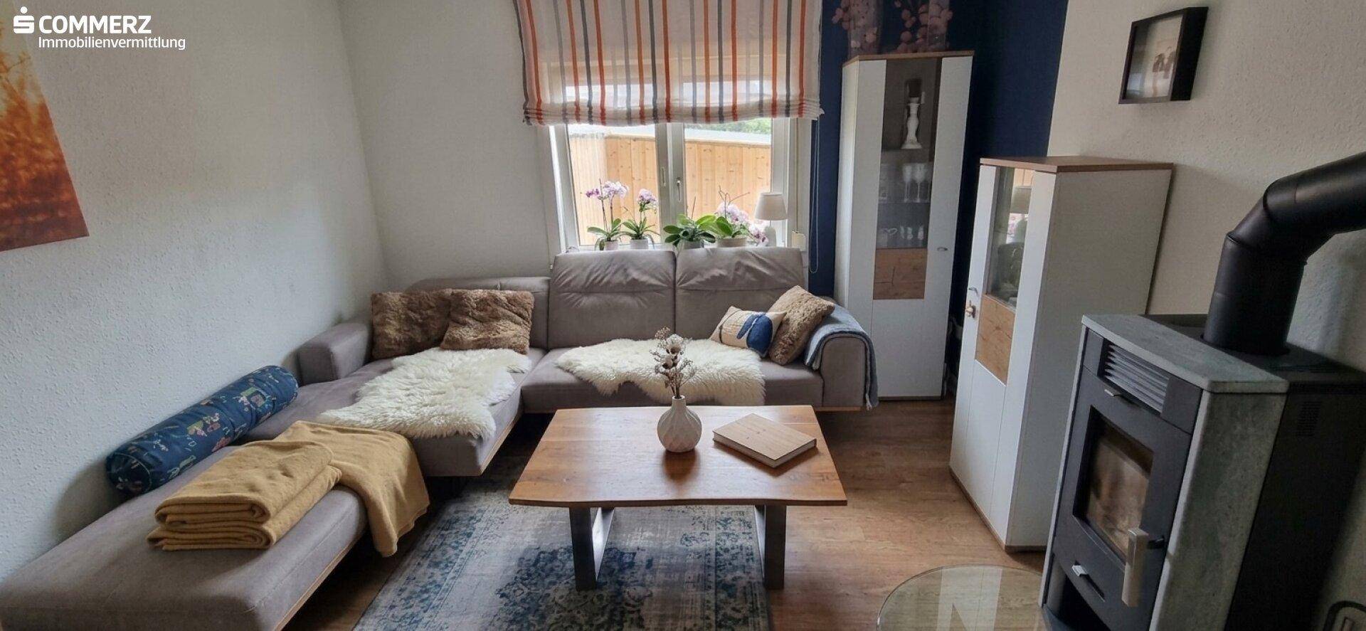 Gemütliches Wohnzimmer mit Ecksofa, Holzboden und einem Kaminofen für warme Abende.