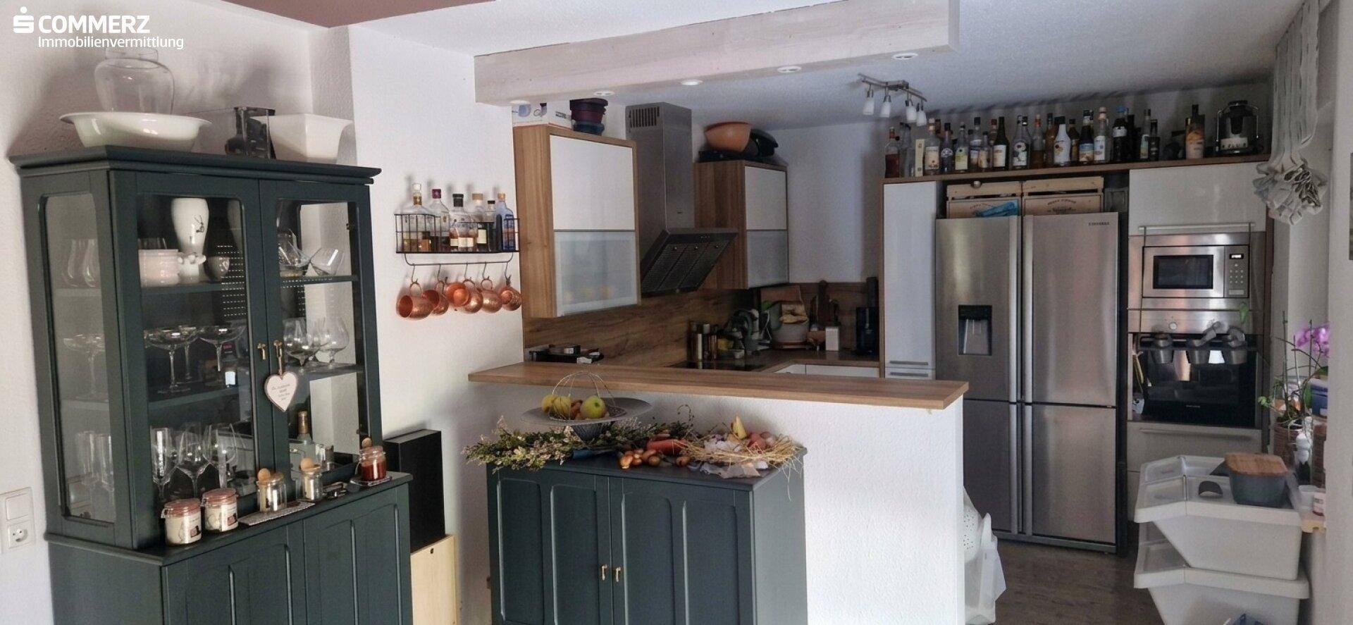 Offene Küche mit Holztheke, modernen Geräten und viel Stauraum für Flaschen und Gläser.