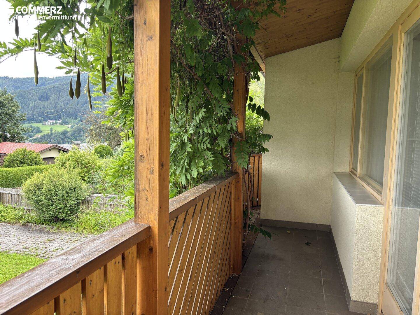 Balkon mit Holzgeländer und weitem Blick ins Grüne sowie auf die umliegende Landschaft.