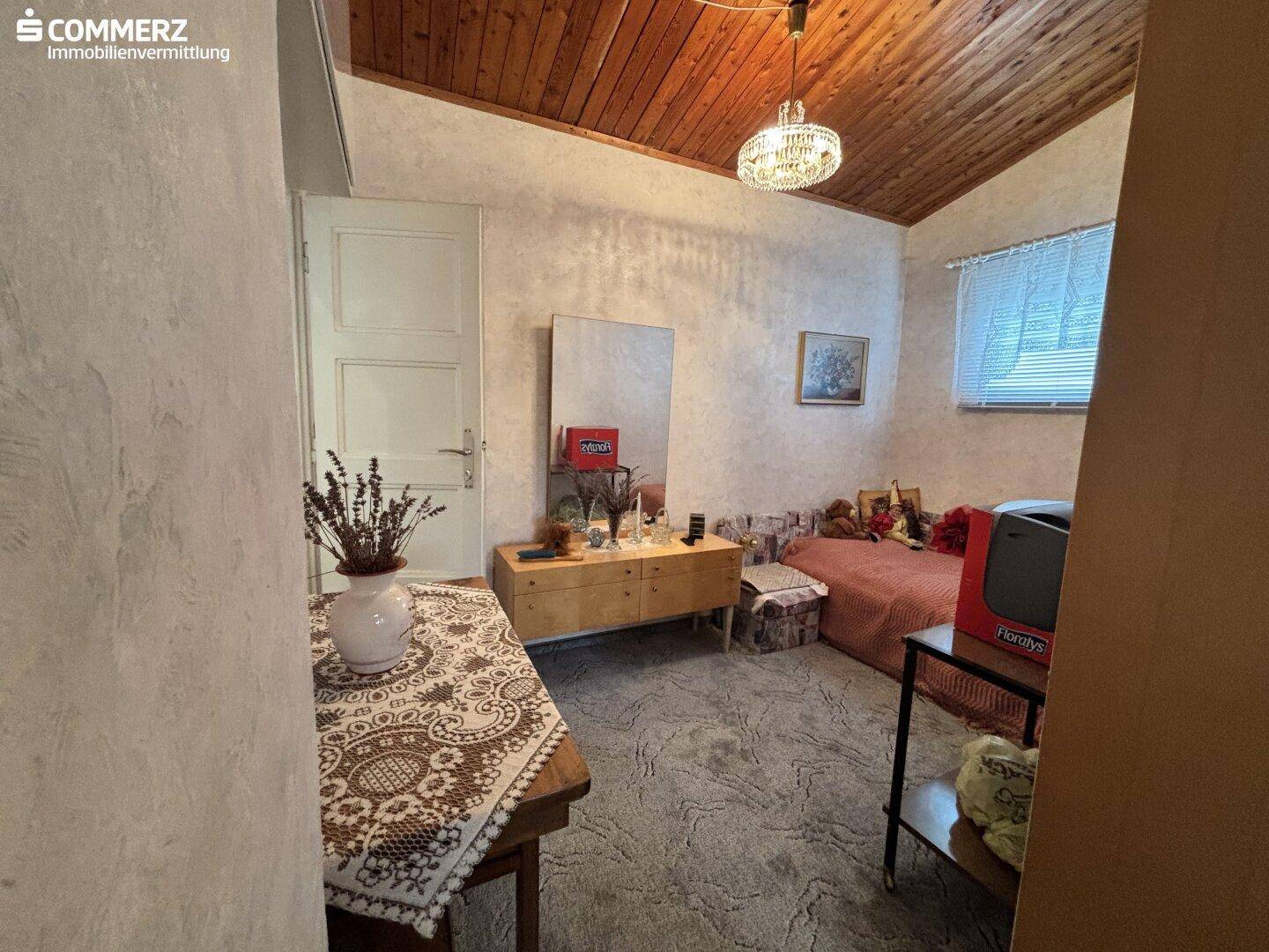 Helles Schlafzimmer mit Holzbalkendecke, Einzelbett und traditioneller Einrichtung.