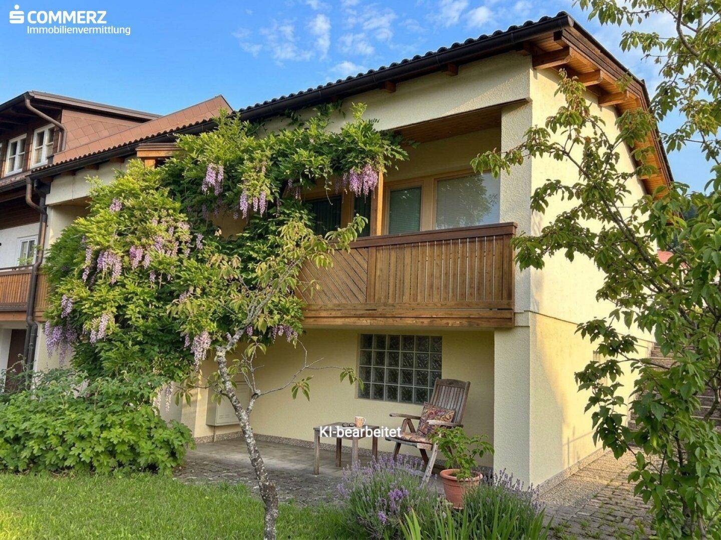 Außenbereich mit kleiner gepflasterter Terrasse, Sitzgelegenheit und blühendem Blauregen.