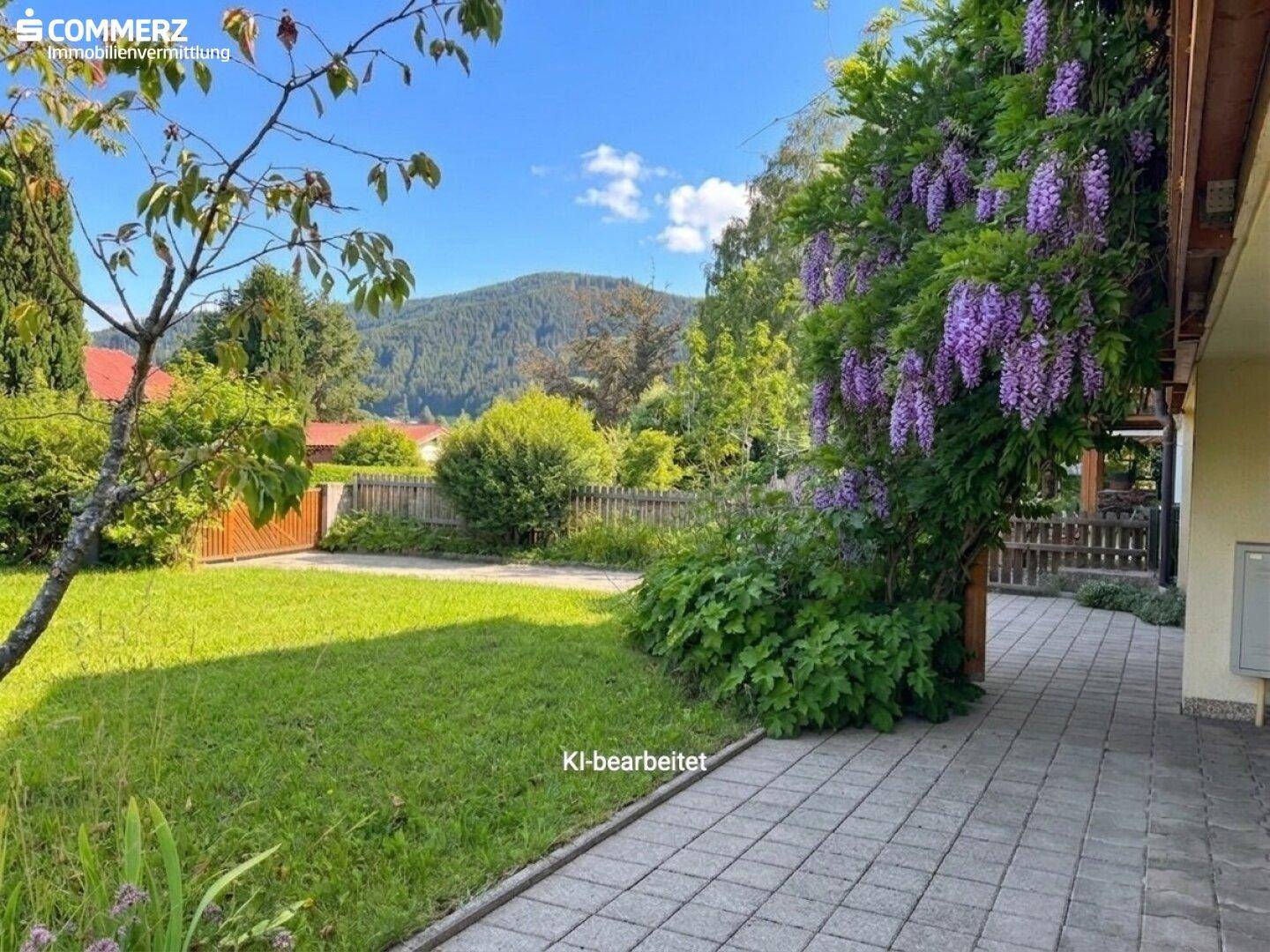 Gepflegter Gartenbereich mit Rasenfläche, gepflastertem Weg und malerischem Bergblick im Hintergrund.