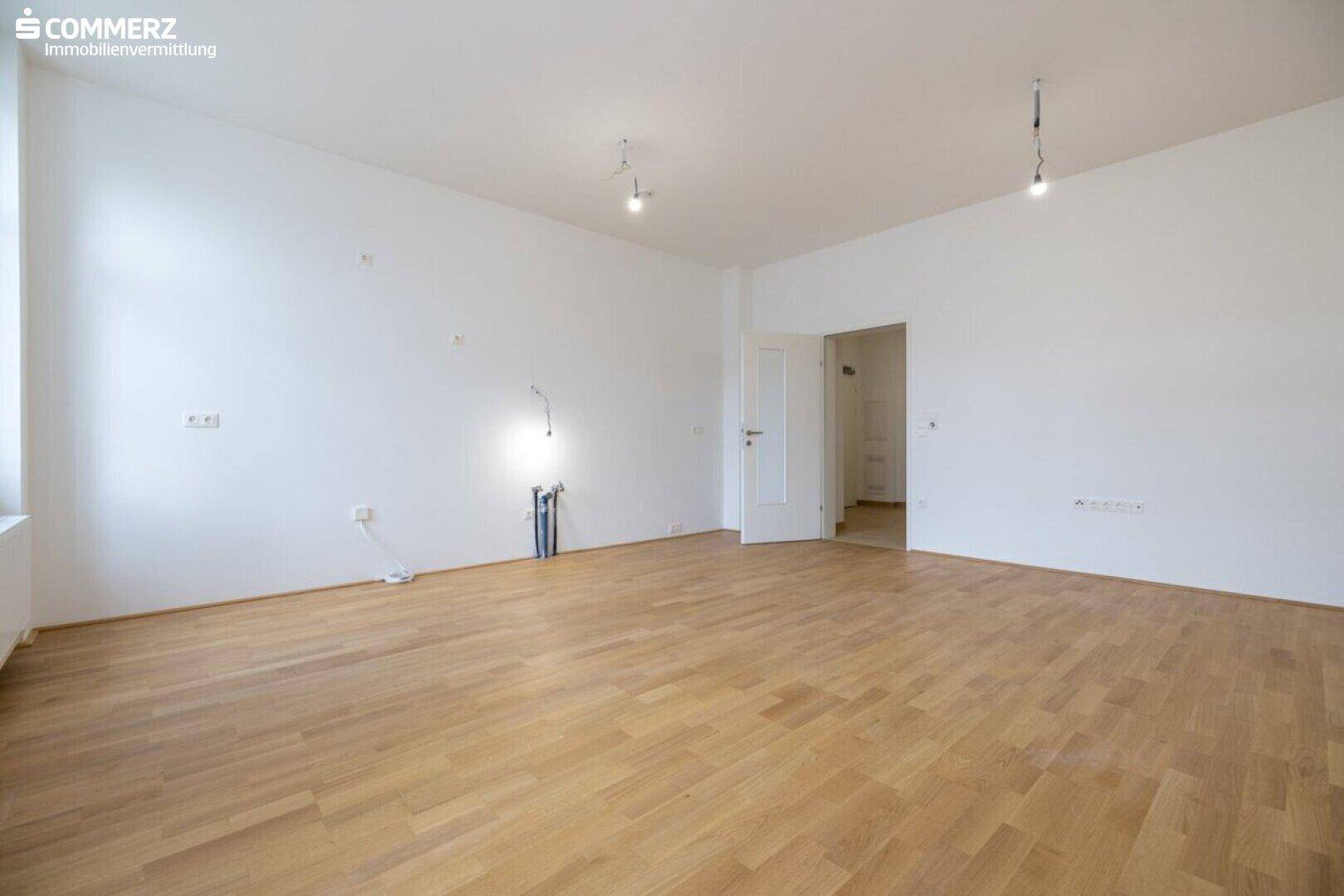 Heller, leerer Raum mit Parkettboden und weißen Wänden, bereit zur individuellen Gestaltung.