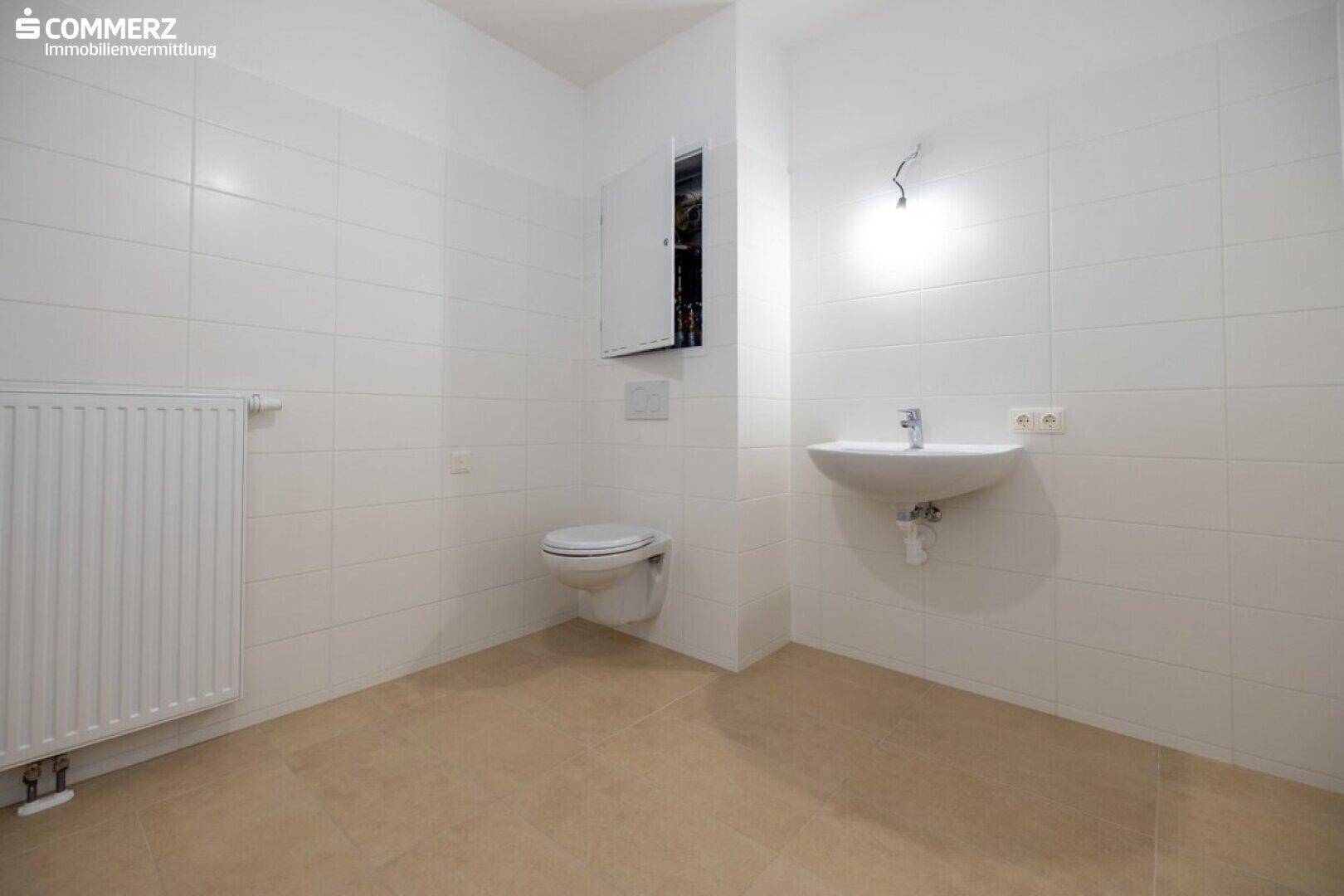 Modernes Badezimmer mit Wand-WC, Waschbecken und weißen Fliesen, in gutem Zustand.