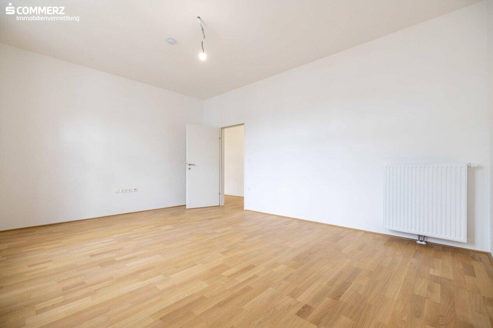 Leerer Raum mit Parkettboden und weiß gestrichenen Wänden, bereit zur Einrichtung.