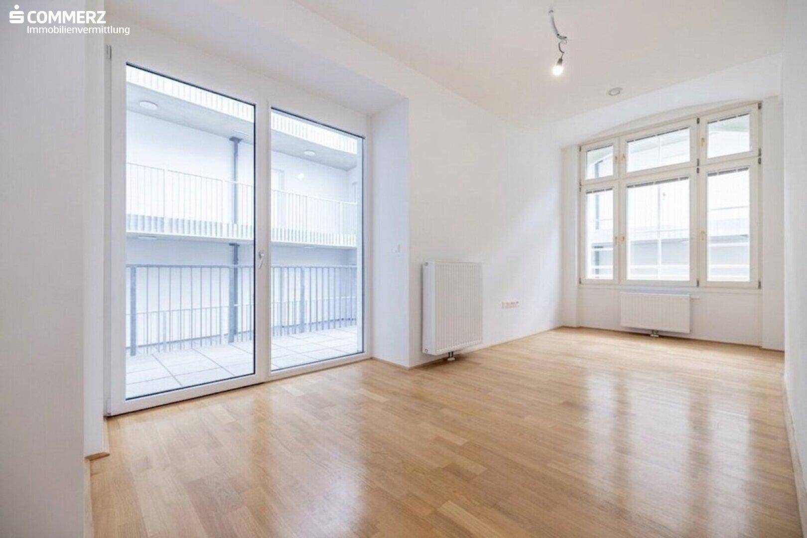 Heller Raum mit Parkettboden und großem Balkonzugang, bietet viel natürliches Licht.