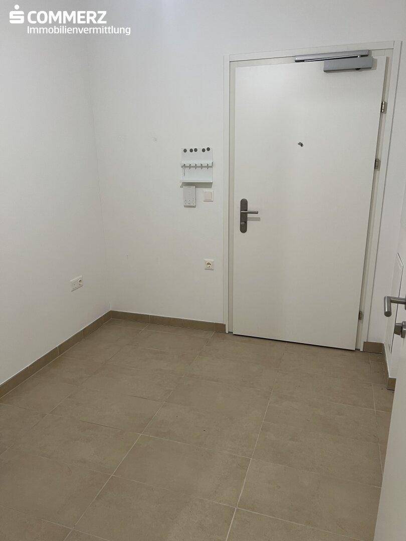 Heller Eingangsbereich mit Fliesenboden und weißer Eingangstür, ideal für Garderobe.