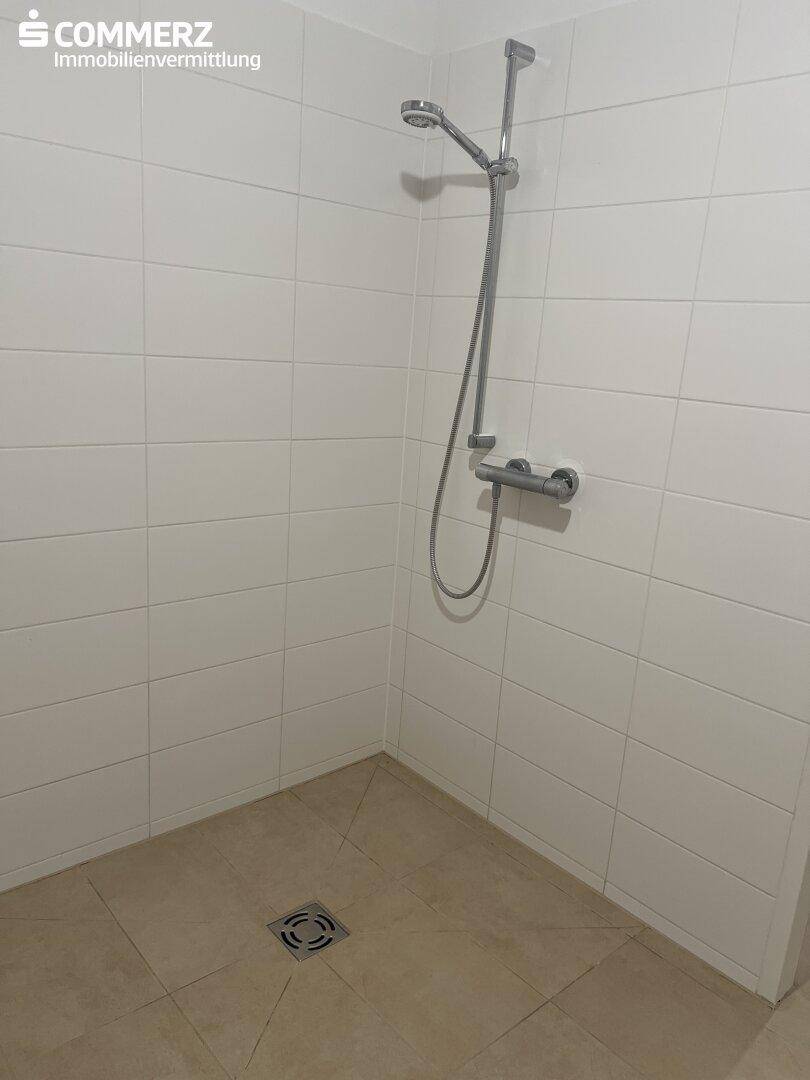 Moderne Duschkabine mit weißen Fliesen und Duscharmatur, bereit zur Nutzung.