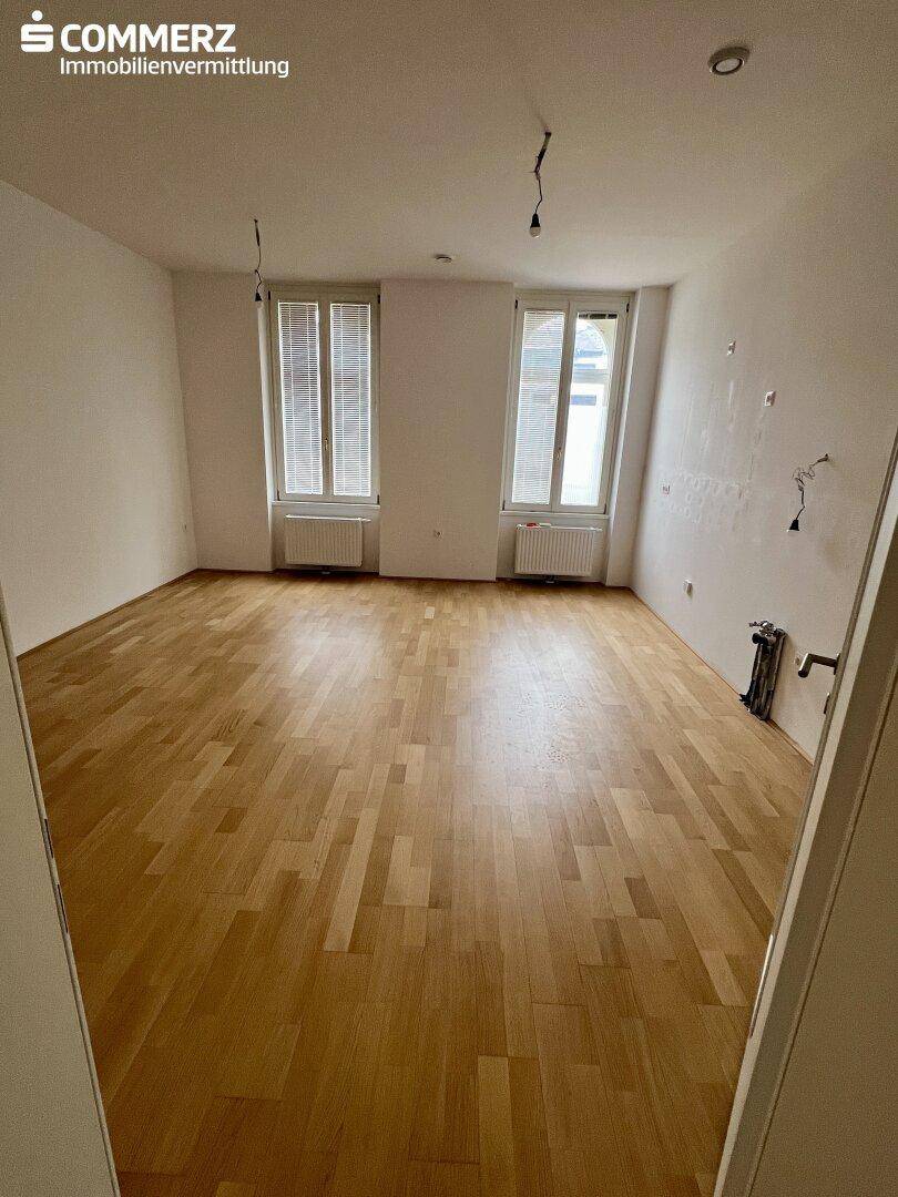 Leerer Raum mit Holzboden und zwei Fenstern, bietet vielseitige Nutzungsmöglichkeiten.