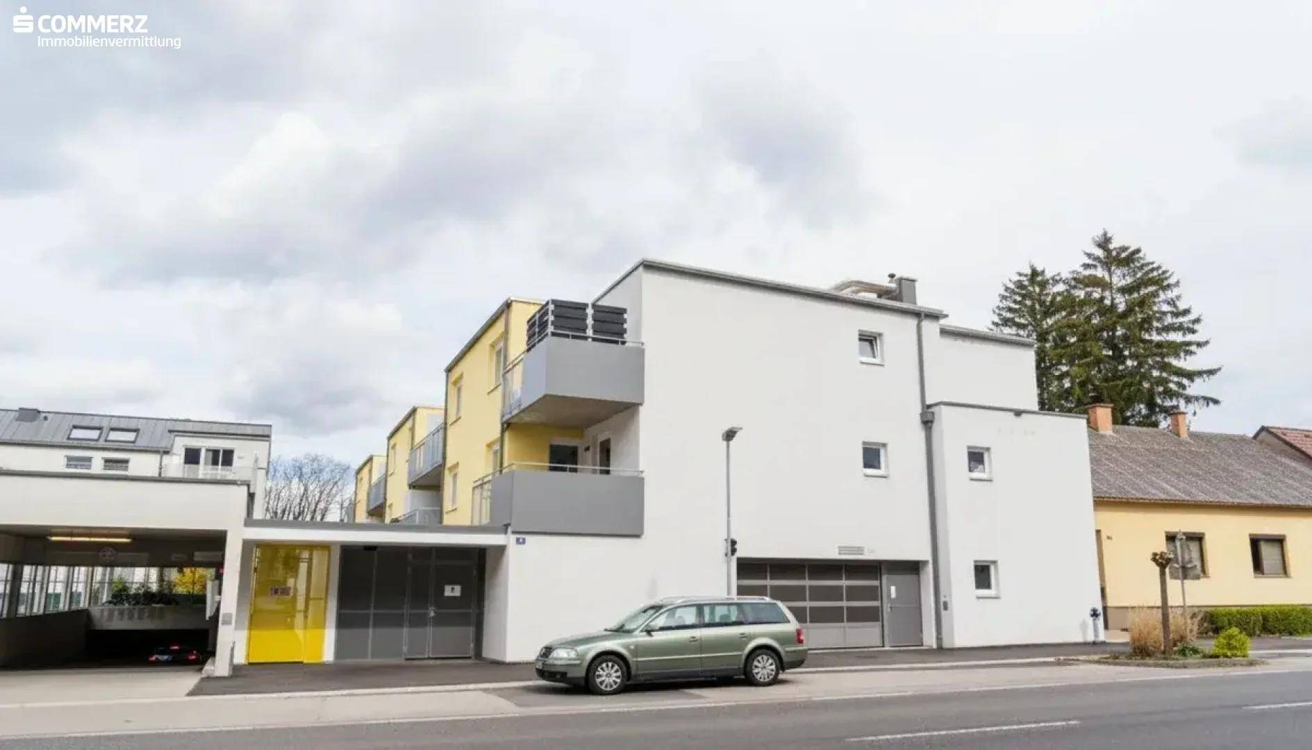 Außenansicht des Gebäudes von der Straße mit Garagen, Carports und moderner Architektur.