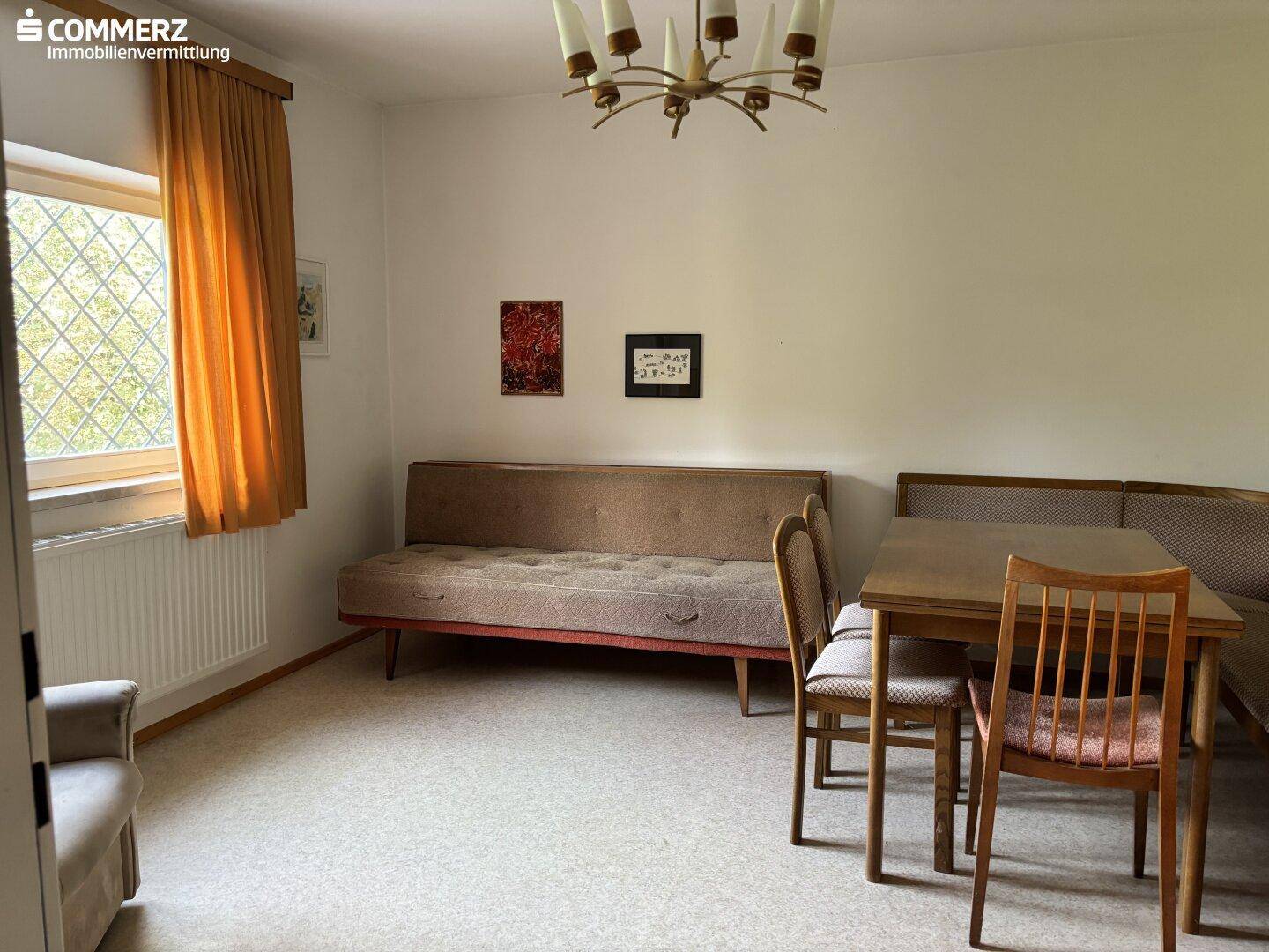 Vielseitiger Raum mit Schlafsofa, Esstisch und Fenster, ideal als Gästezimmer nutzbar.