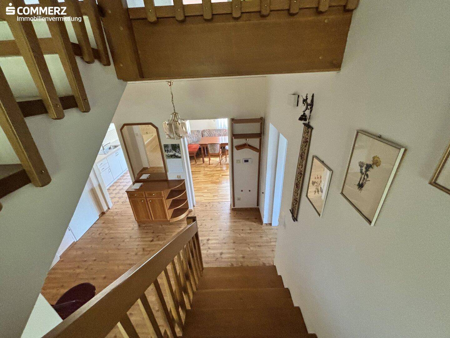 Helle Diele mit Holztreppe und Parkettboden, die verschiedene Wohnbereiche verbindet.