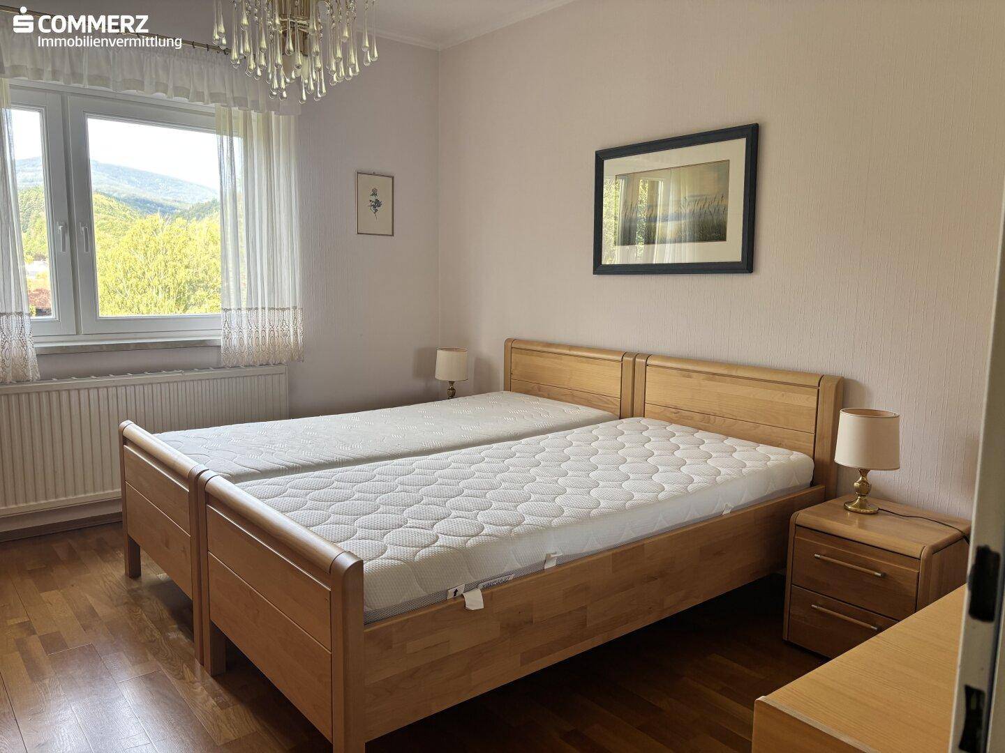 Gemütliches Schlafzimmer mit Holzbetten, Parkettboden und Fenster mit Bergblick.