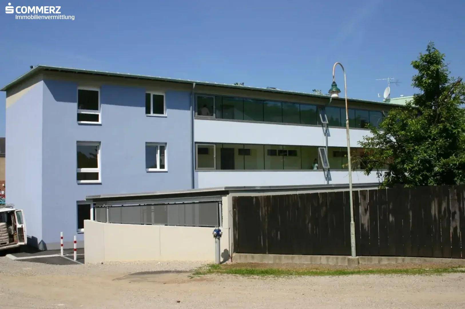 Seitenansicht eines modernen Wohngebäudes mit blauer Fassade und großen Fensterfronten.