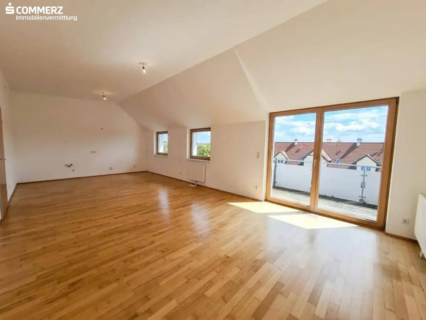 Helles und geräumiges Wohnzimmer mit Holzboden und Zugang zu einem Balkon.