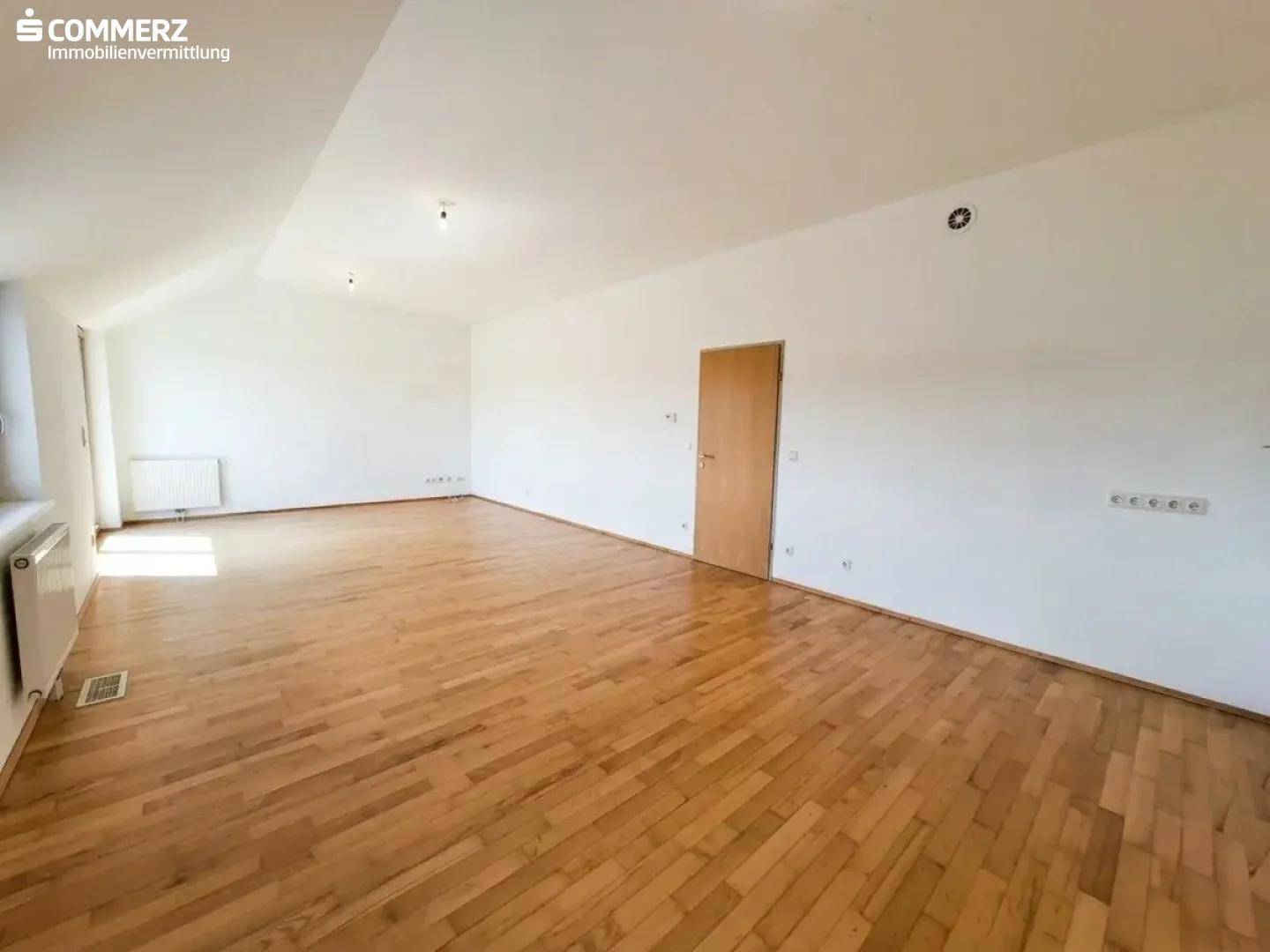 Geräumiger Wohnraum mit hellem Holzboden und weiß gestrichenen Wänden, ideal für individuelle Gestaltung.