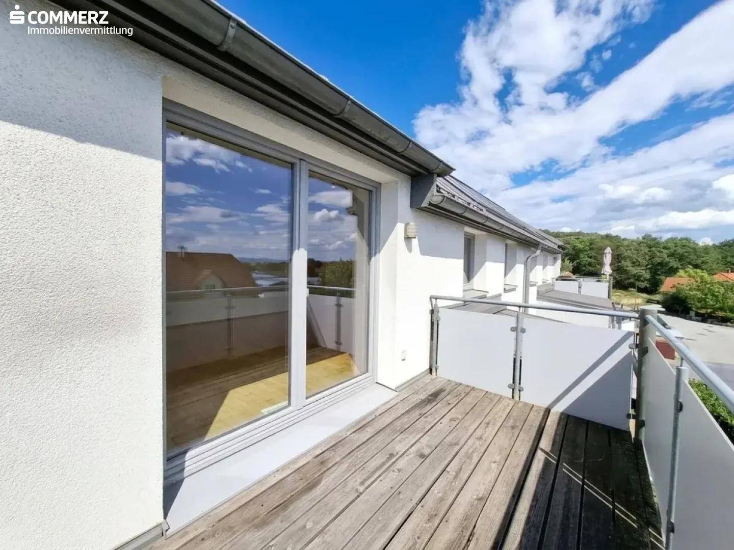 Moderner Balkon mit Glasgeländer und Holzboden, bietet einen schönen Ausblick auf die Umgebung.