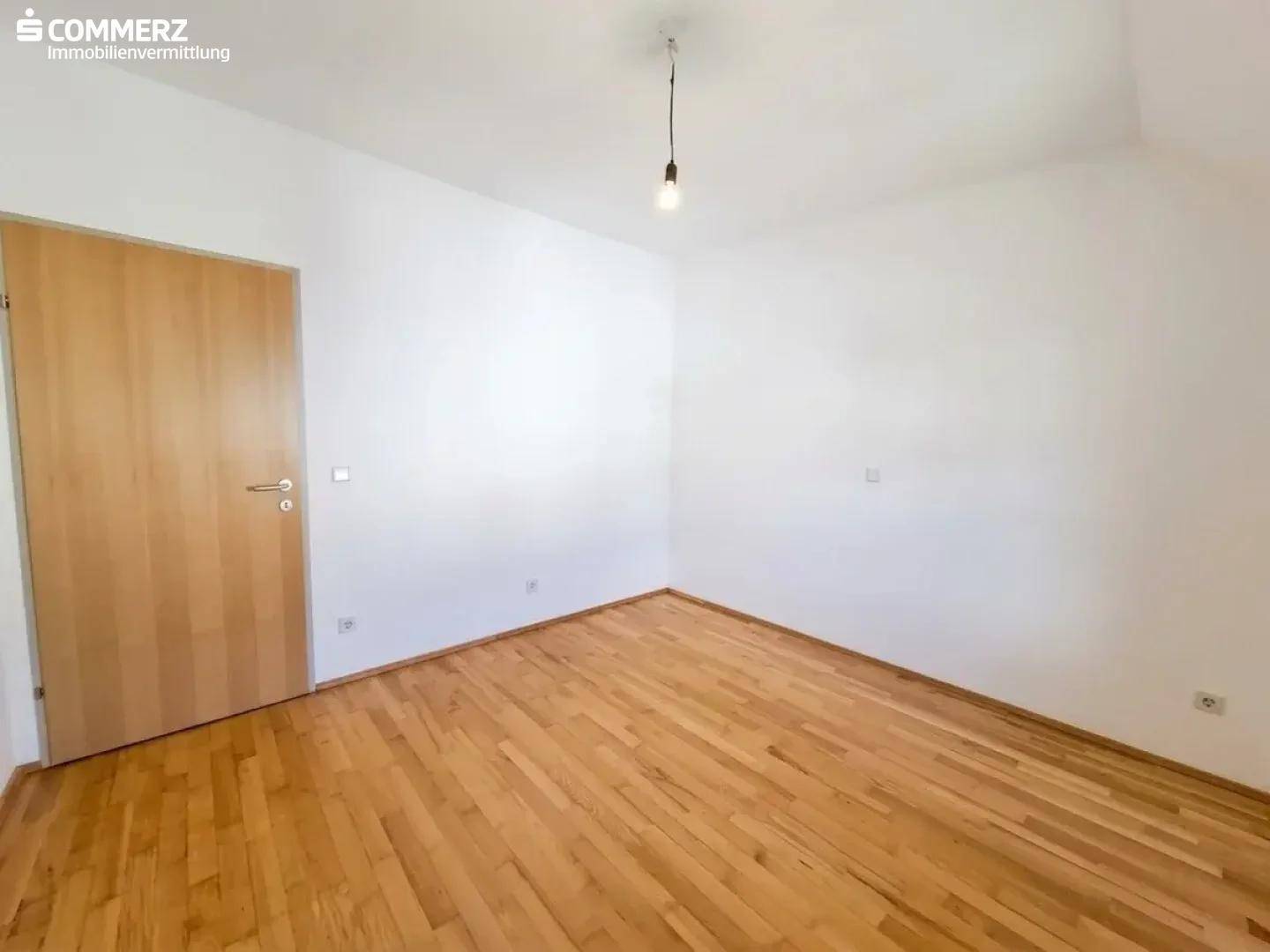 Schlafzimmer mit Holzboden und Holztür, bietet eine neutrale Basis für verschiedene Einrichtungsstile.