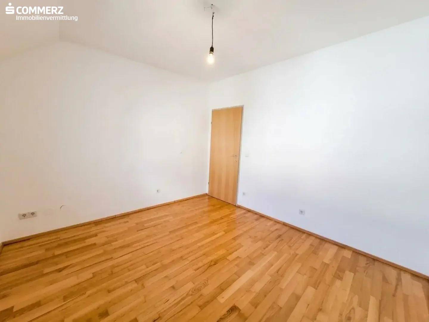 Geräumiges Schlafzimmer mit Holzboden und weiß gestrichenen Wänden, bereit zur individuellen Gestaltung.
