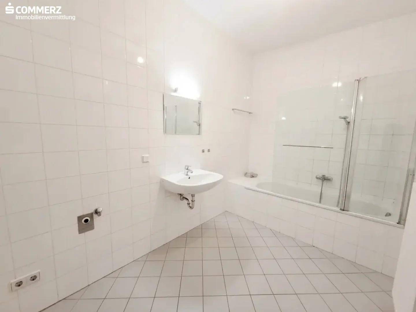 Modern gefliestes Badezimmer mit Badewanne, Duschabtrennung und Waschbecken.