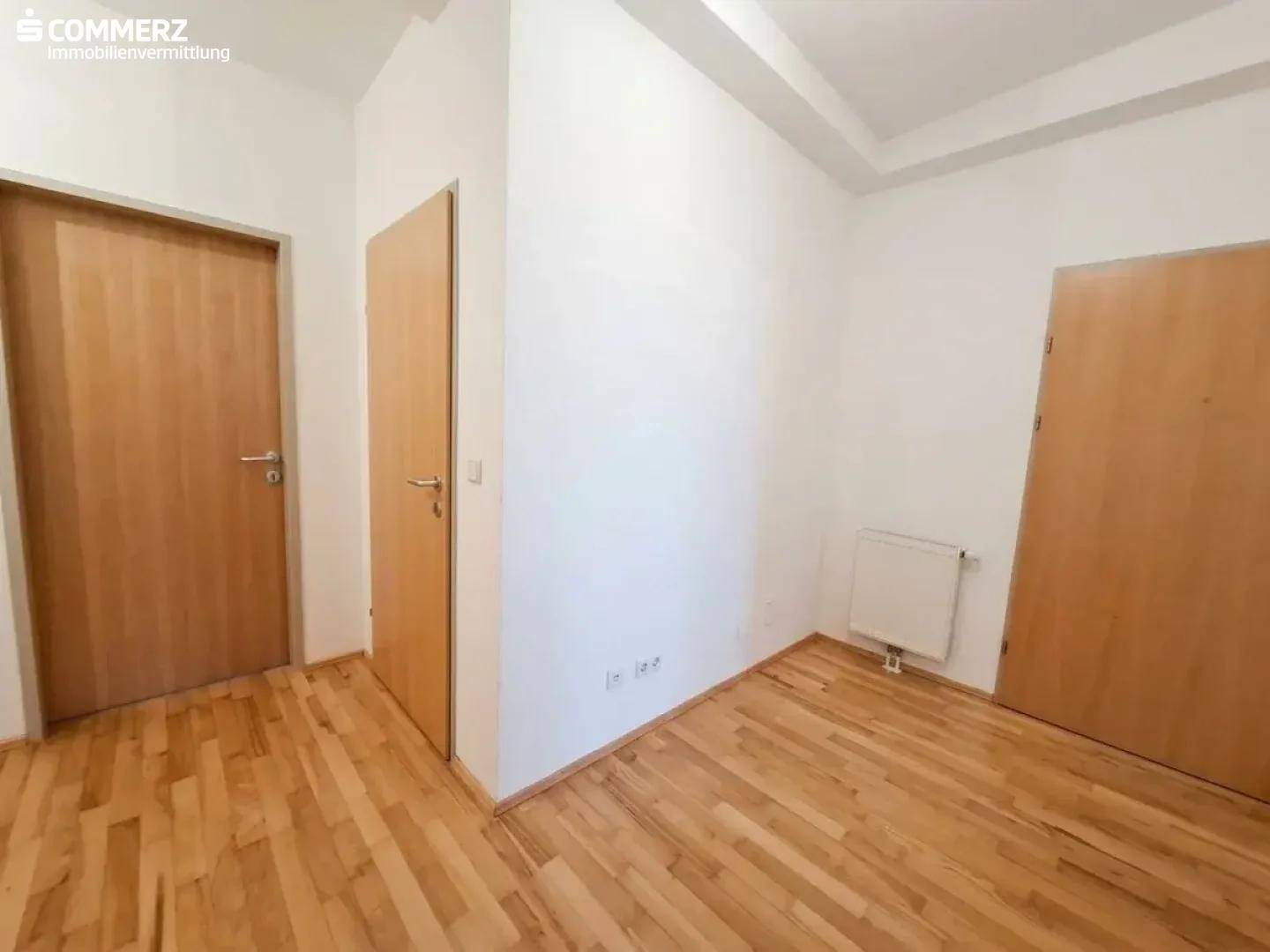 Heller Flur mit Holzboden und mehreren Türen, der verschiedene Räume miteinander verbindet.
