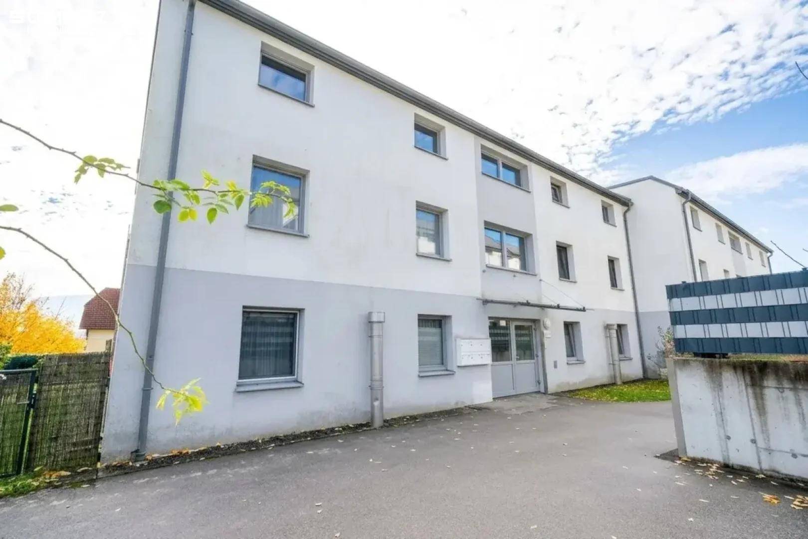 Mehrfamilienhaus mit schlichter Fassade und mehreren Fenstern in einer ruhigen Wohngegend.