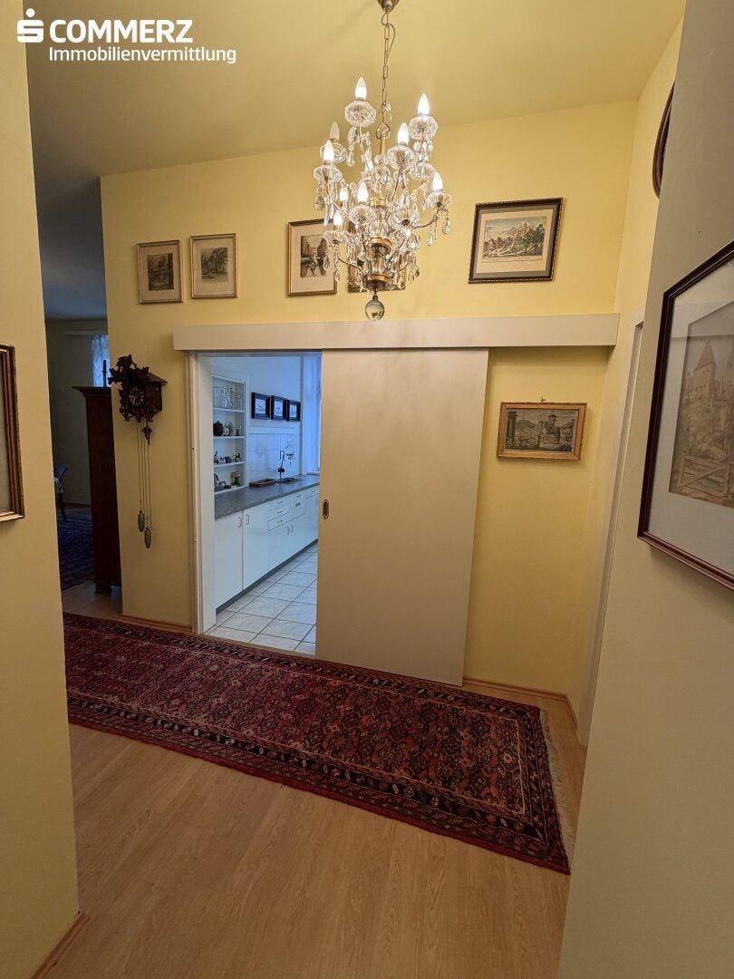 Heller Flur mit Holzboden, Teppichläufer und Blick in eine angrenzende Küche.