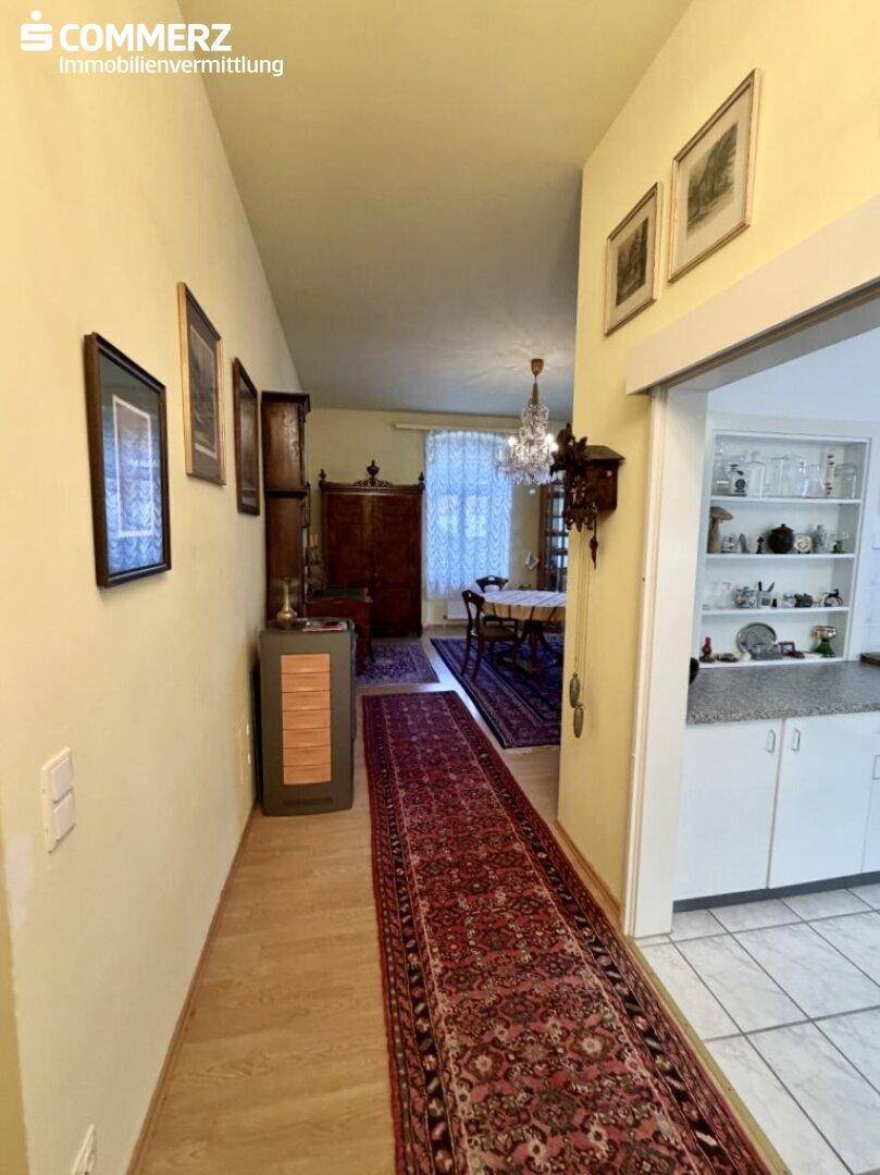 Langer Flur mit Holzboden, Teppichläufer und Durchgang zu Esszimmer und Küche.